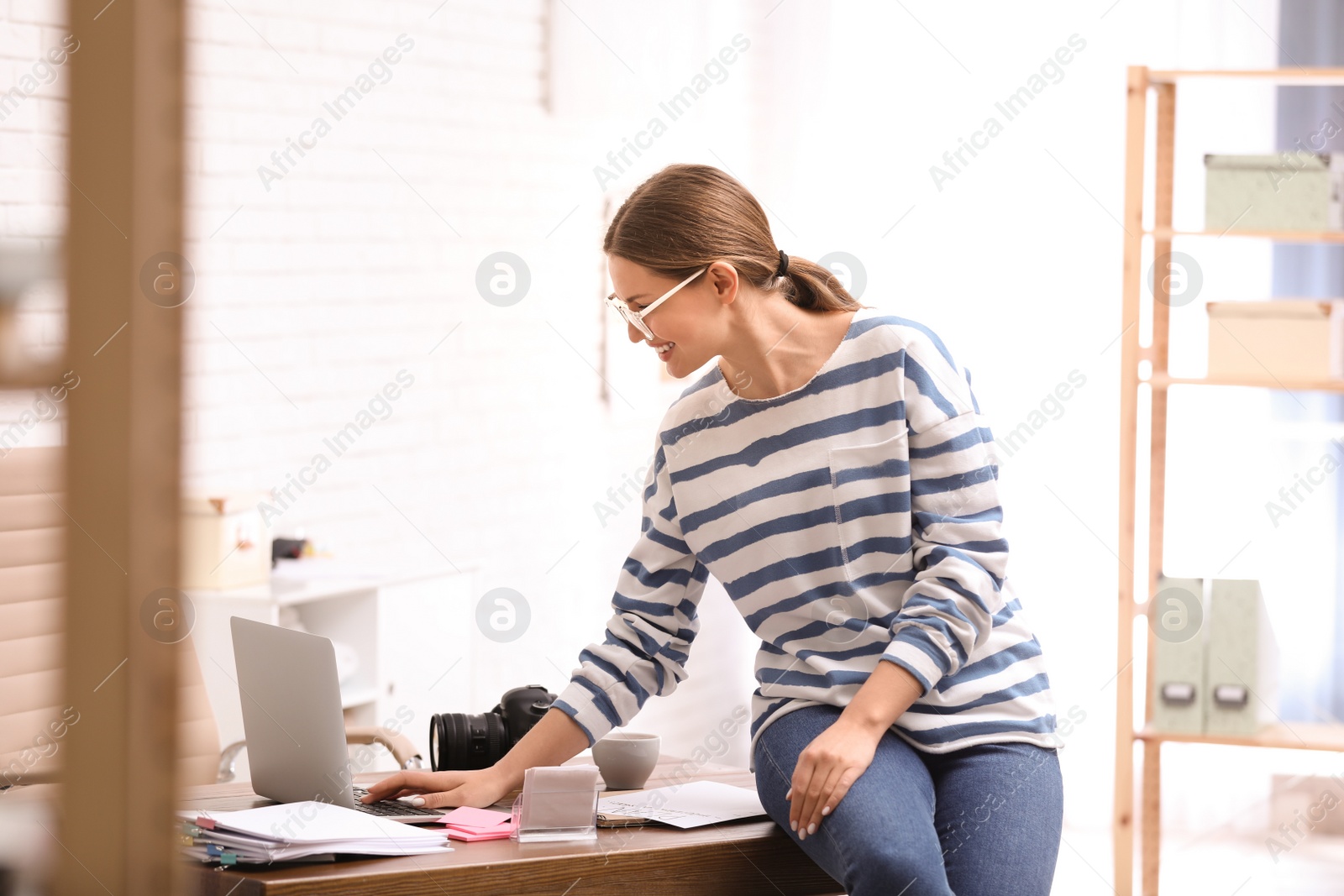 Photo of Young journalist working with laptop in light office