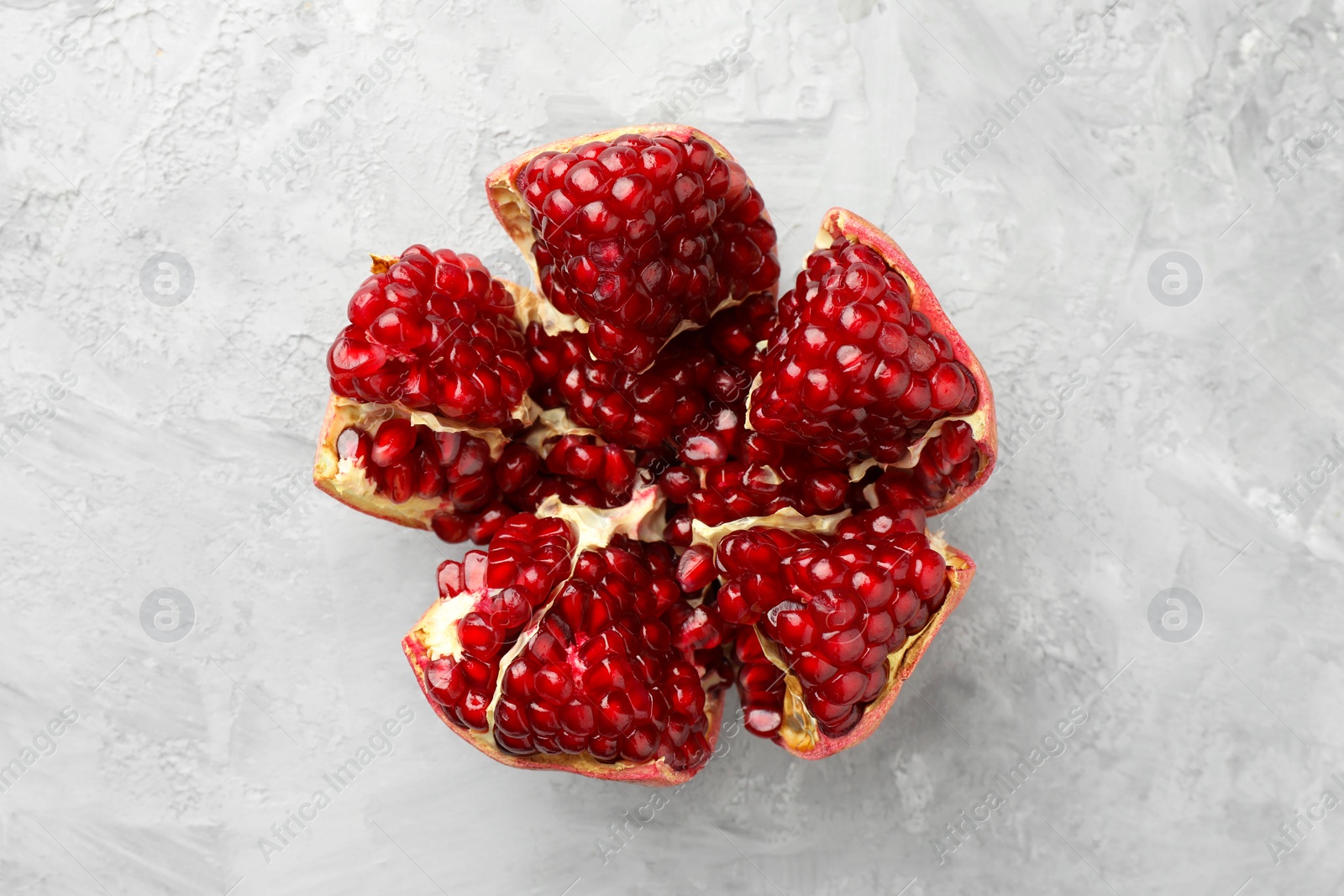 Photo of Cut fresh pomegranate on grey textured table, top view