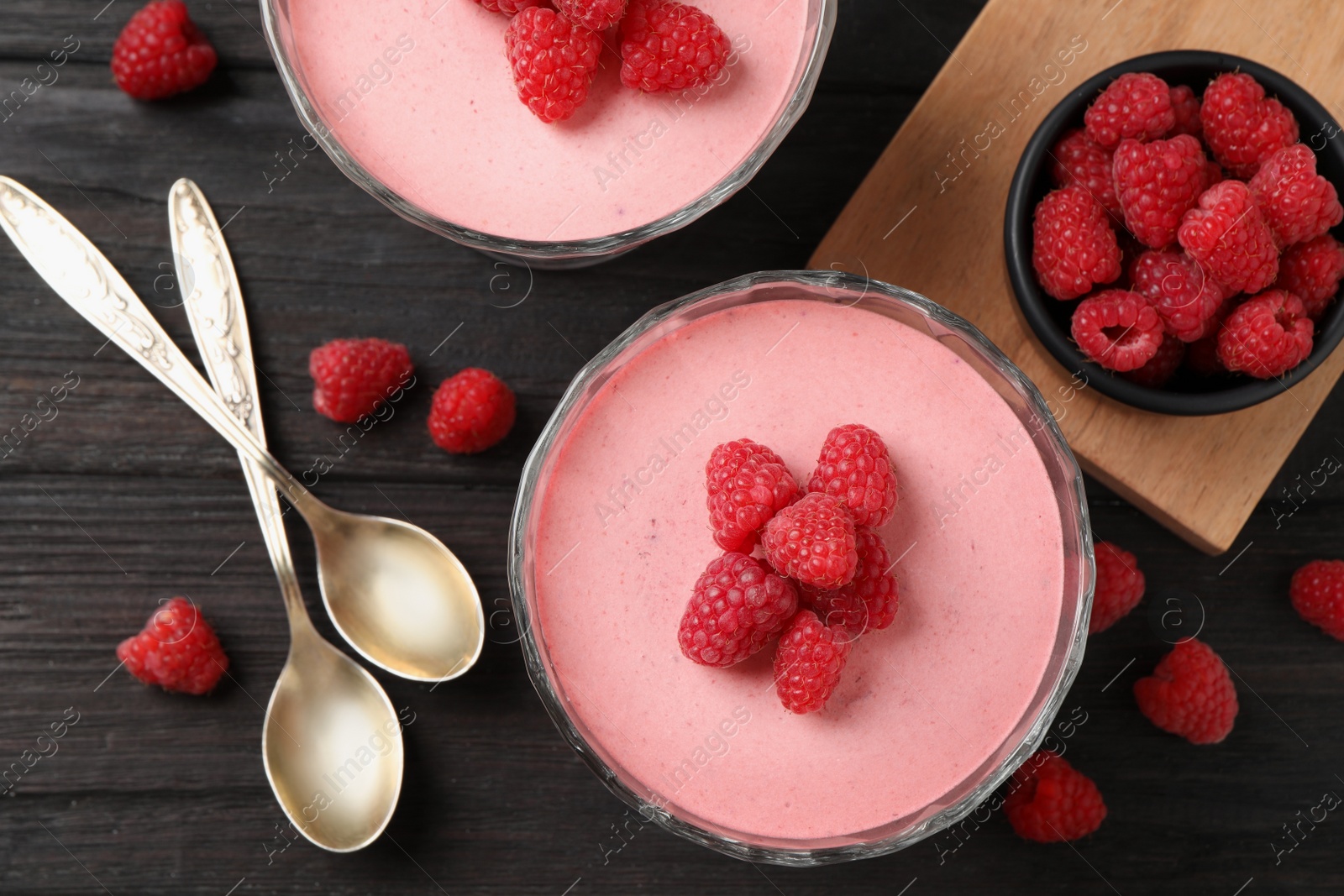 Photo of Delicious raspberry mousse on black wooden table, flat lay