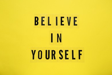 Photo of Phrase Believe In Yourself and hearts on yellow background, top view. Motivational quote