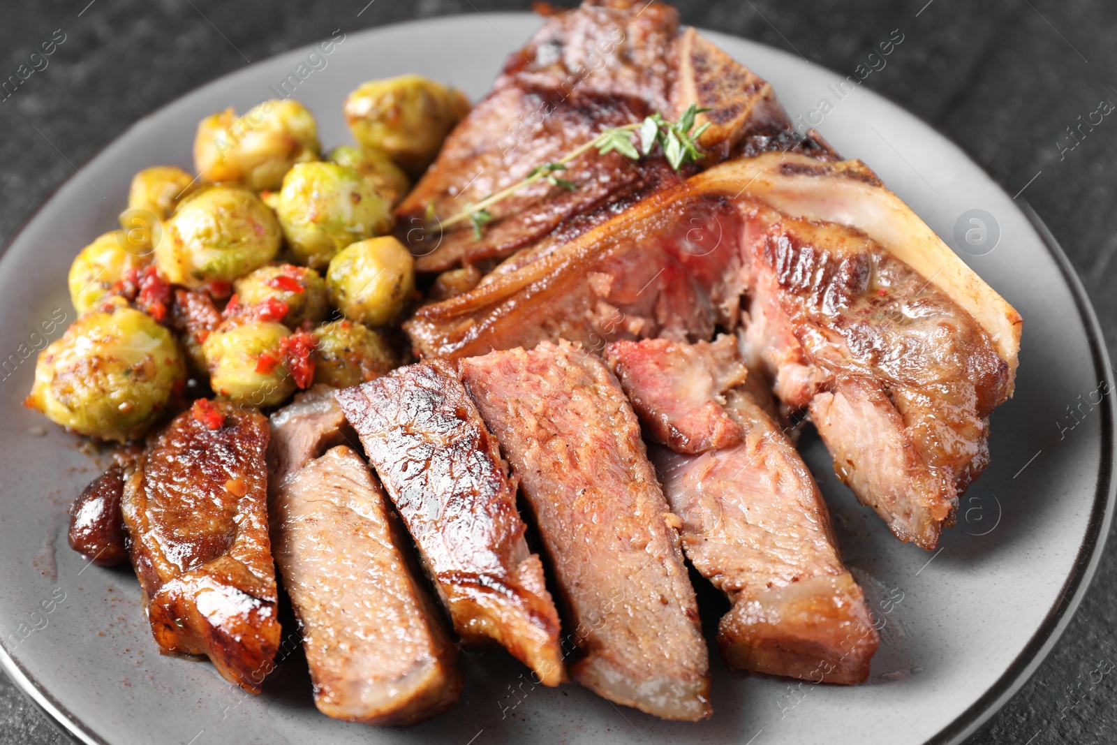 Photo of Delicious fried beef meat, vegetables and thyme on table, closeup