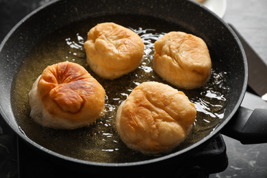 Cooking delicious donuts in hot oil, closeup