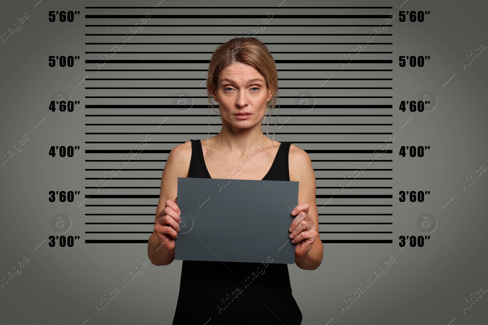 Image of Criminal mugshot. Arrested woman with blank card against height chart