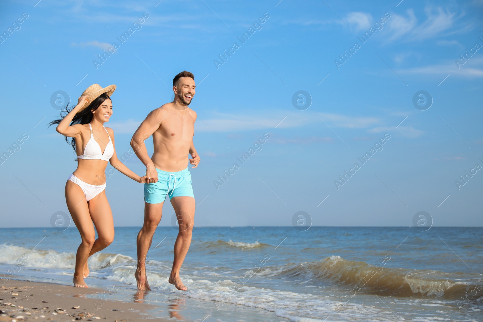 Photo of Happy young couple running together on beach