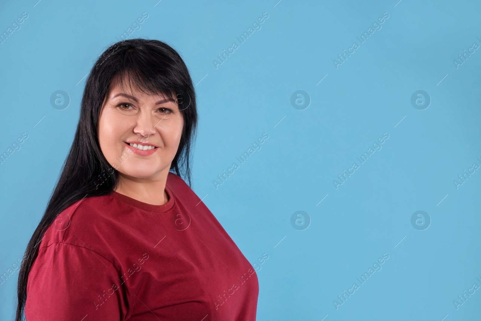 Photo of Beautiful overweight mature woman with charming smile on turquoise background. Space for text