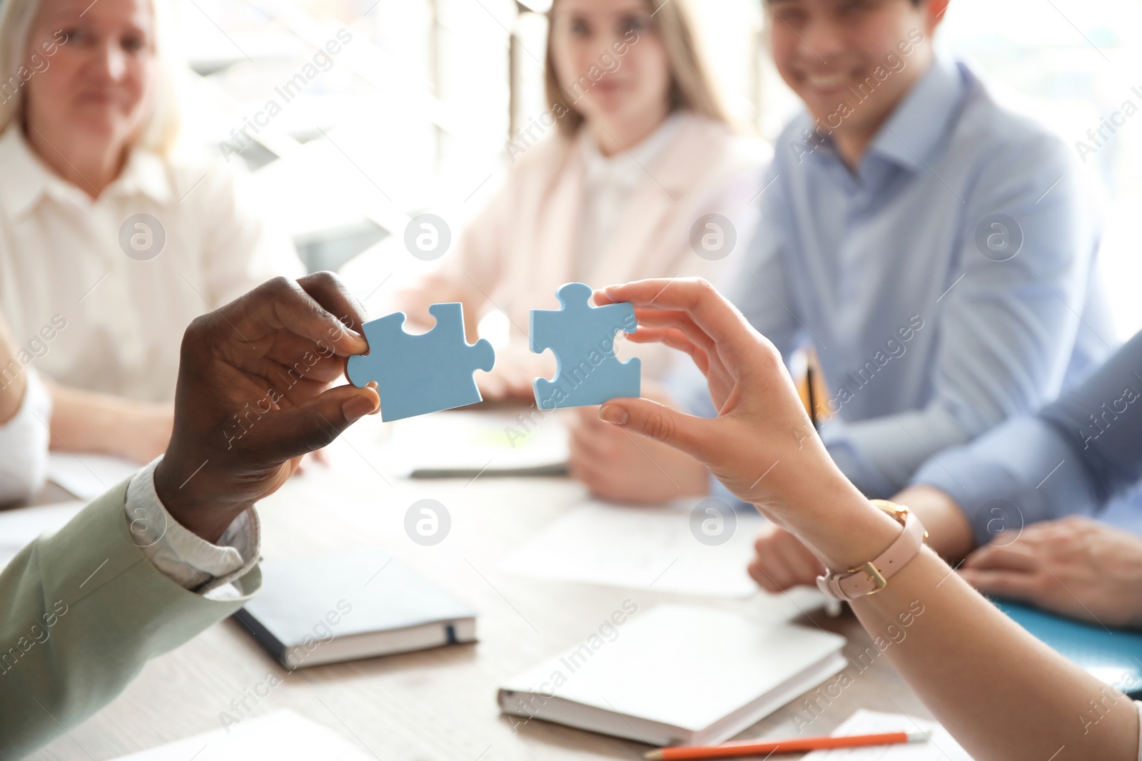 Photo of People with puzzle indoors, closeup of hands. Unity concept