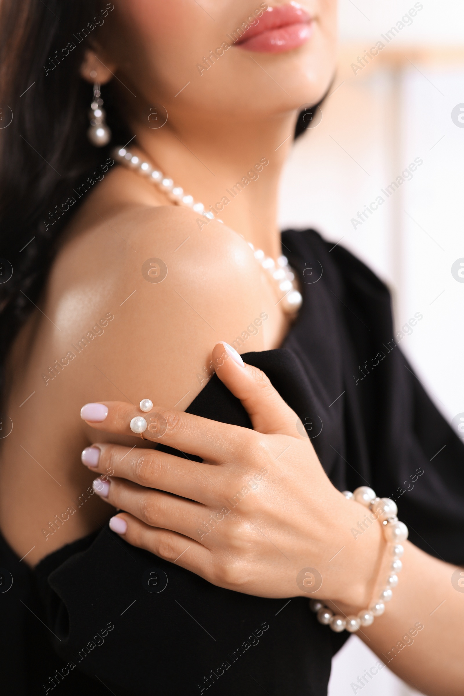 Photo of Young woman wearing elegant pearl jewelry indoors, closeup