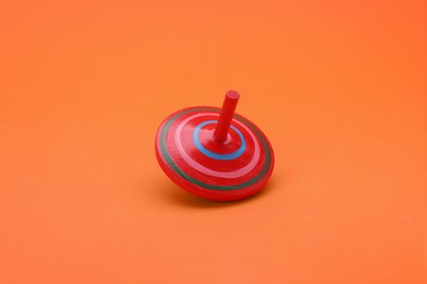 Photo of One bright spinning top on orange background. Toy whirligig