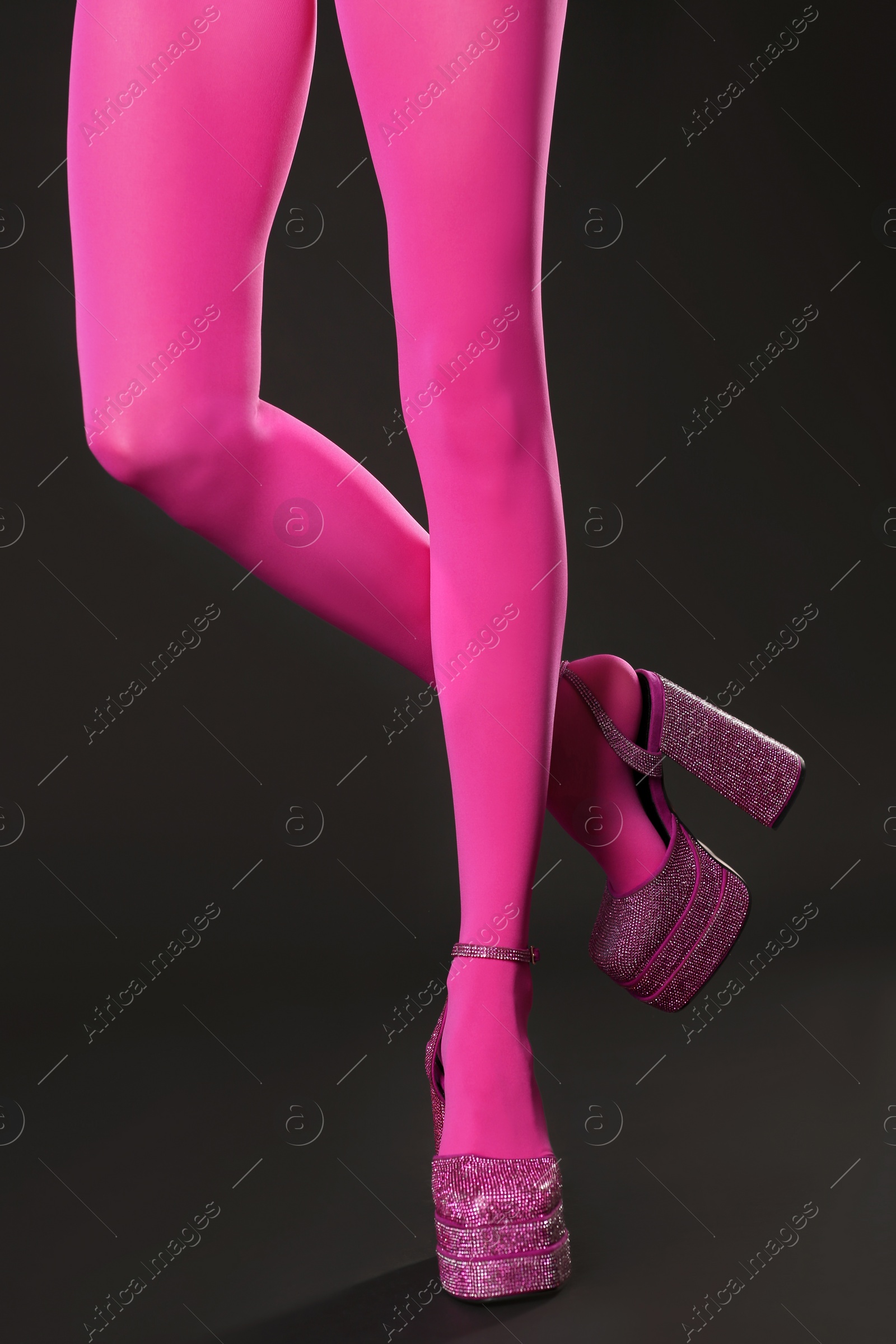 Photo of Woman wearing pink tights and high heeled shoes with platform and square toes on dark grey background, closeup