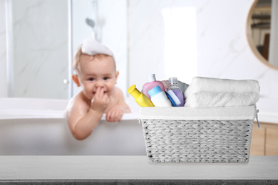 Image of Basket with different baby cosmetic products and bathing accessories on table in bathroom