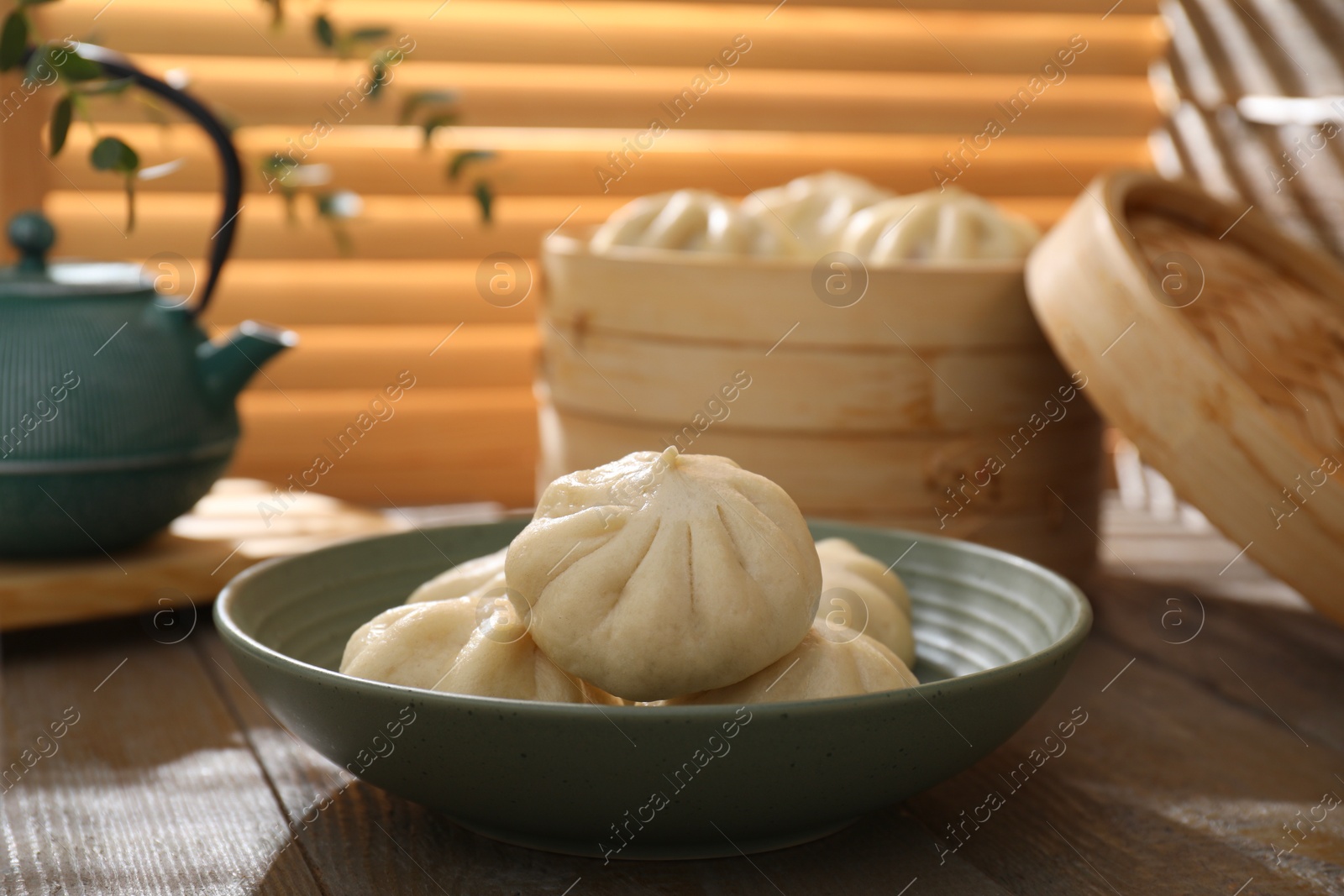 Photo of Delicious bao buns (baozi) in bowl on wooden table, closeup