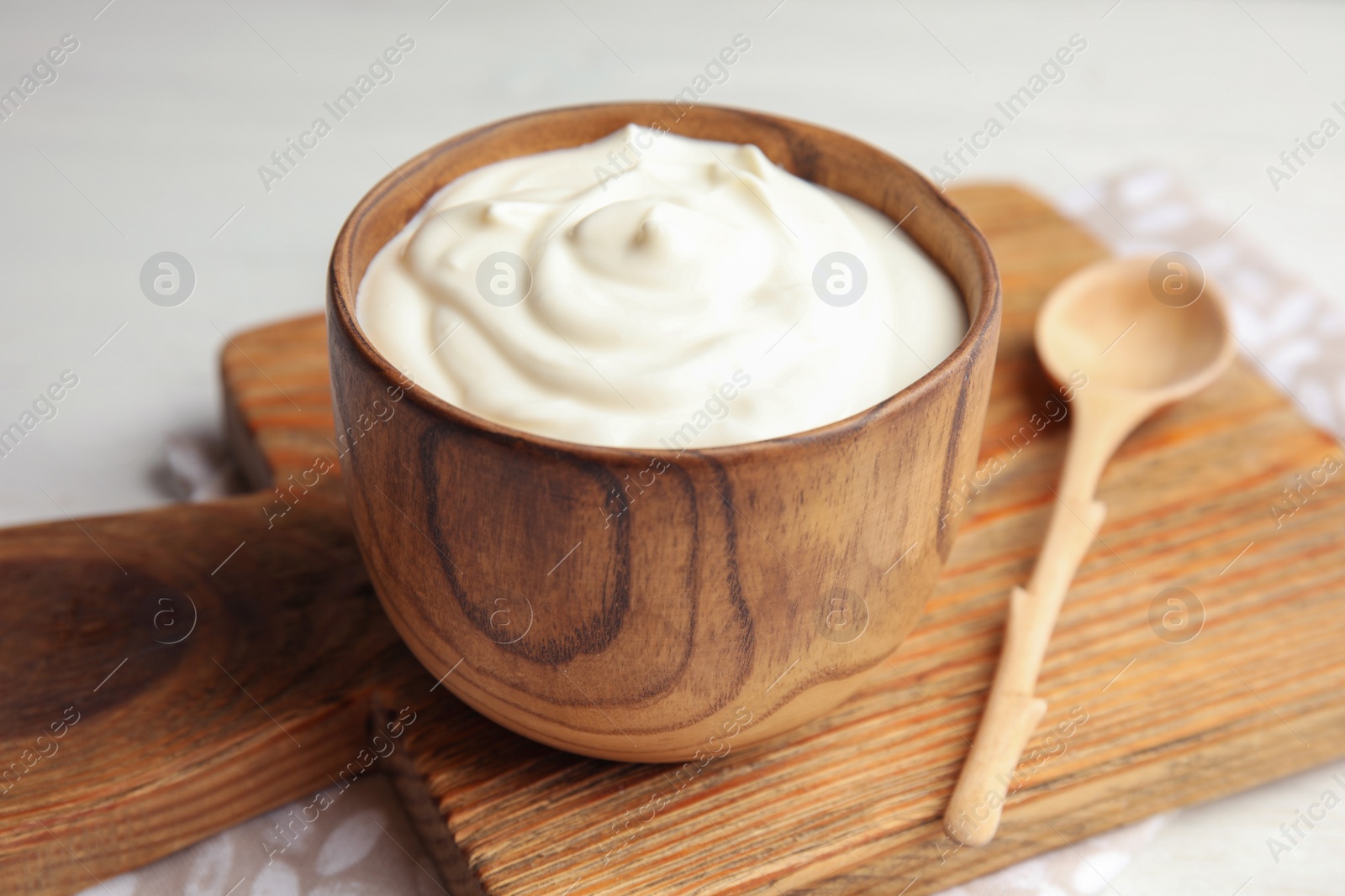 Photo of Wooden bowl with creamy yogurt served on table