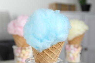 Sweet cotton candy in waffle cone on blurred background, closeup