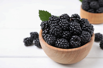 Photo of Fresh ripe blackberries in bowl on white wooden table, closeup