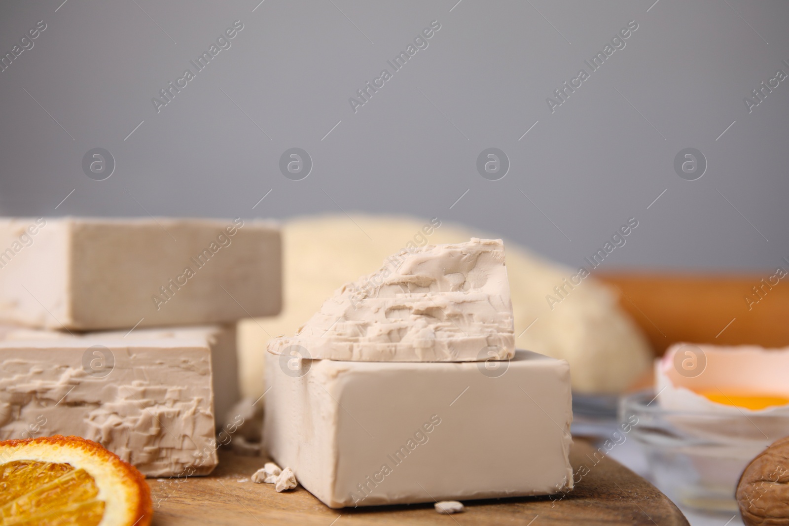 Photo of Blocks of compressed yeast and ingredients on wooden table, closeup