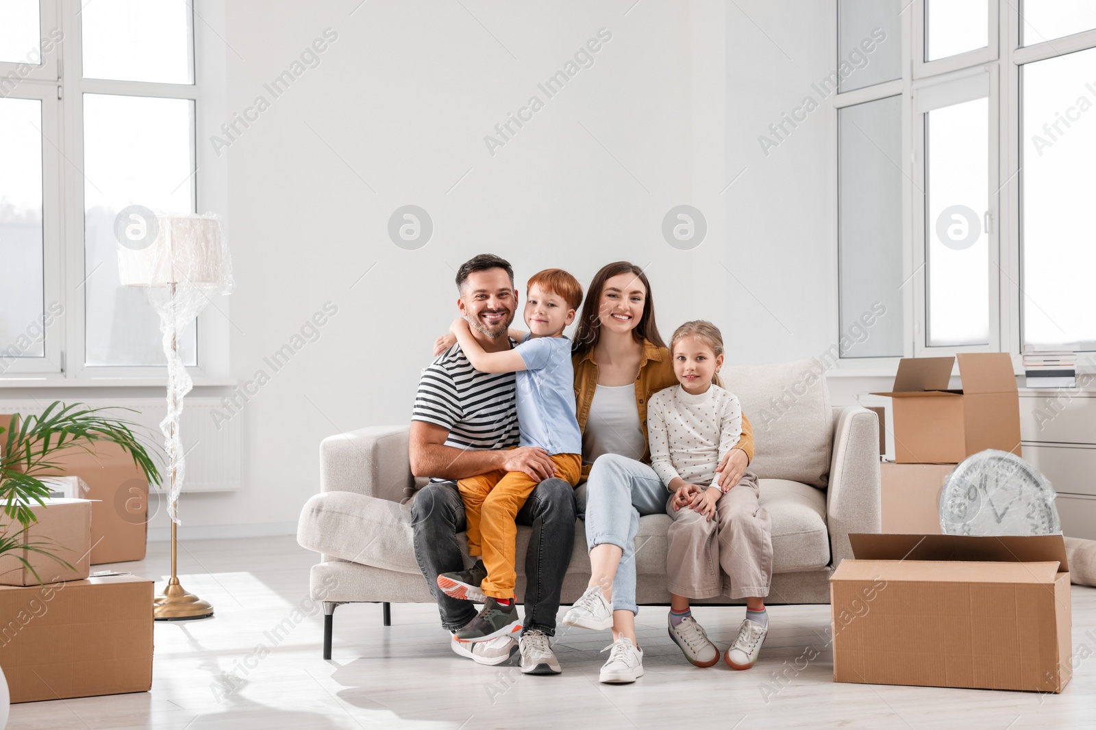 Photo of Happy family sitting on couch in new apartment. Moving day