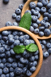 Flat lay composition with juicy blueberries and green leaves on color table