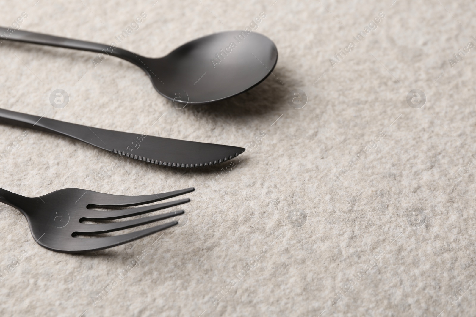 Photo of Stylish cutlery set on beige textured table, closeup. Space for text