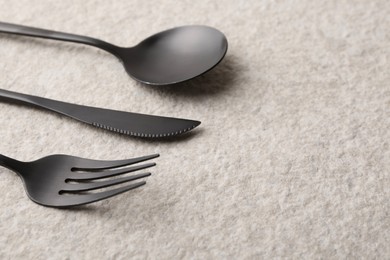 Photo of Stylish cutlery set on beige textured table, closeup. Space for text