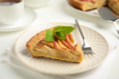 Slice of delicious apple pie on white table