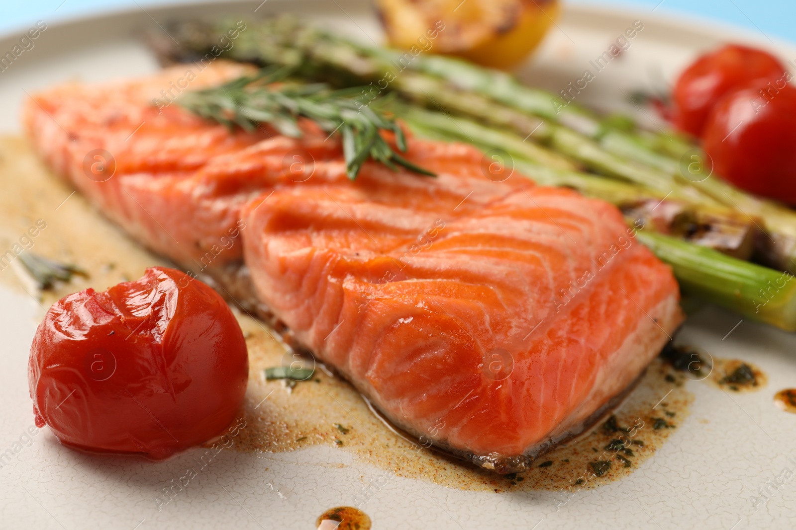 Photo of Tasty grilled salmon with tomatoes, asparagus and spices on plate, closeup