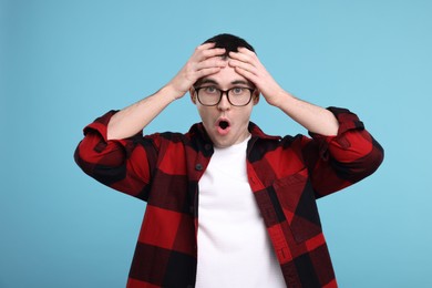 Surprised man in glasses on light blue background