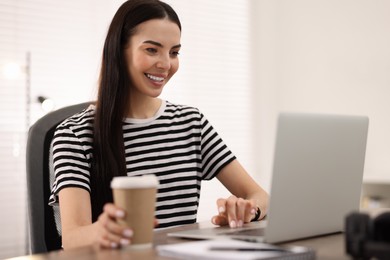 Young woman watching webinar at table in room