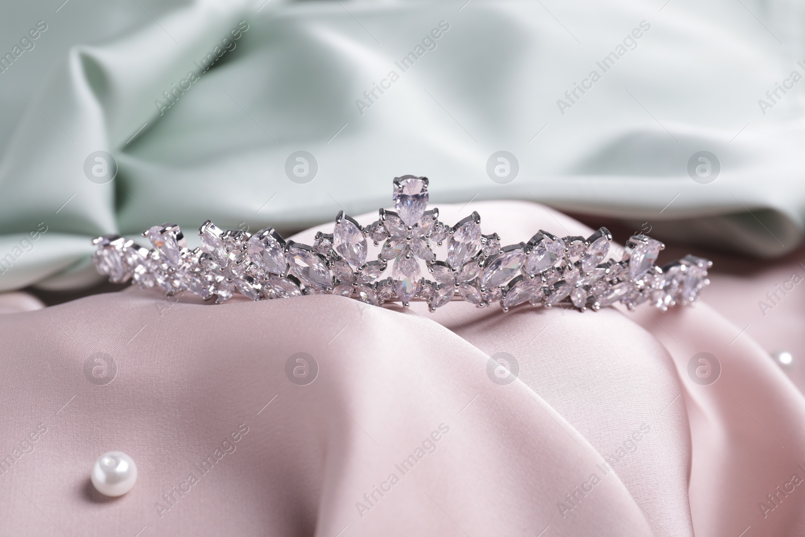 Photo of Beautiful silver tiara with diamonds on pink silk cloth