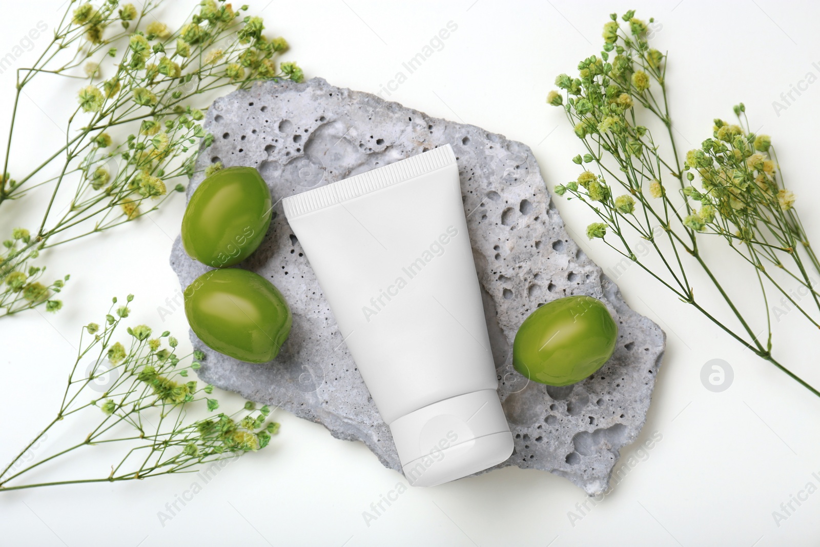 Photo of Tube of cream, olives and flowers on white background, flat lay