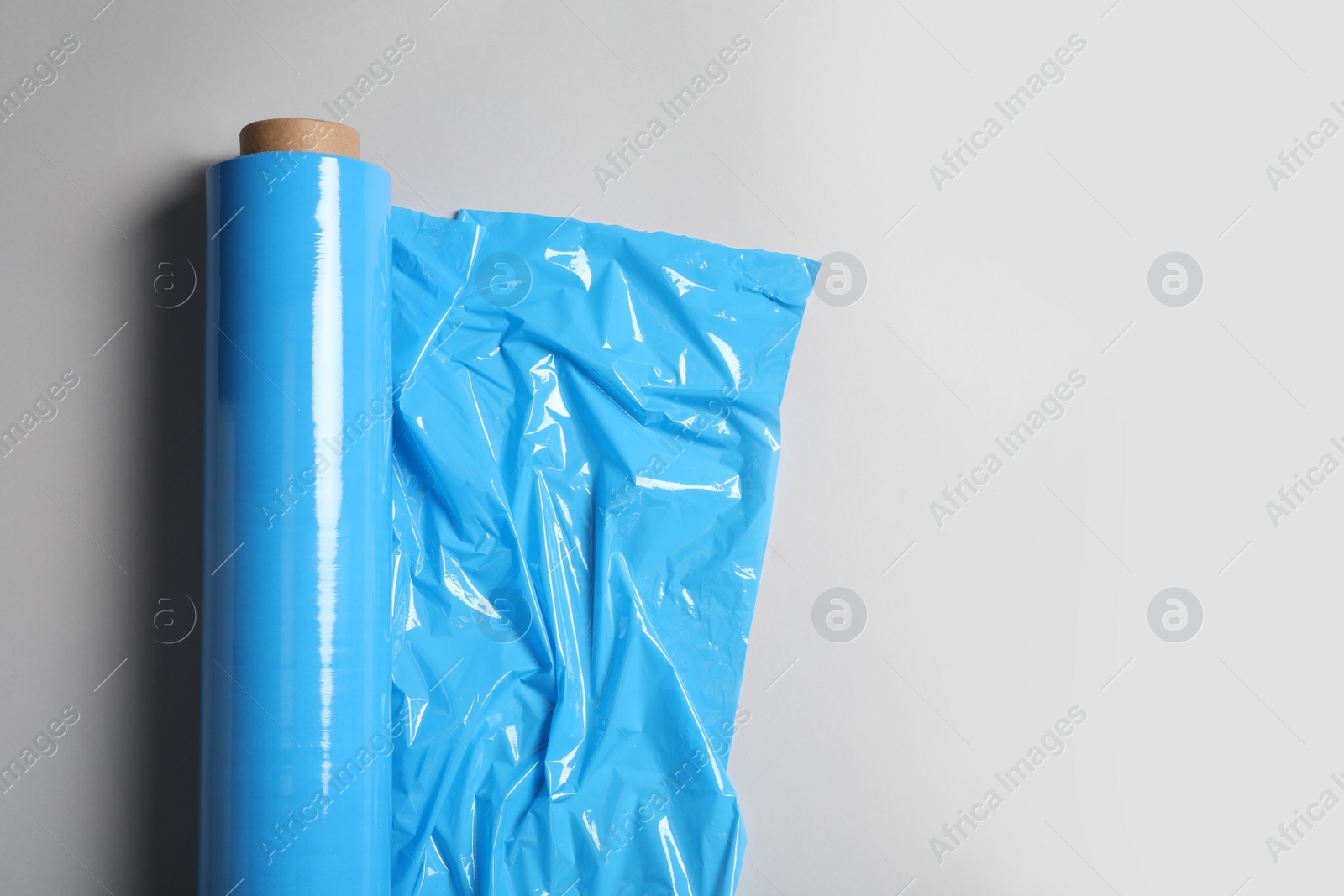 Photo of Roll of plastic stretch wrap film on white background, top view. Space for text