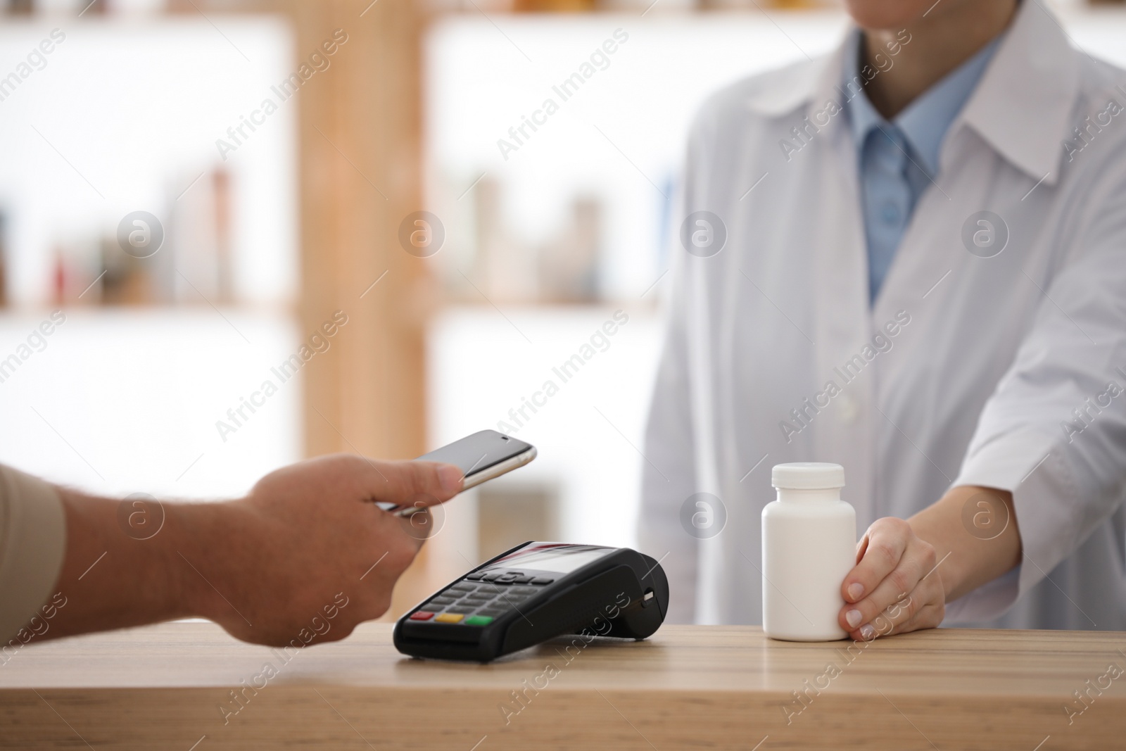 Photo of Customer using terminal for contactless payment with smartphone in pharmacy, closeup