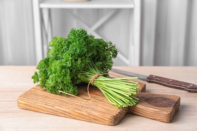 Photo of Wooden board with fresh green parsley on table