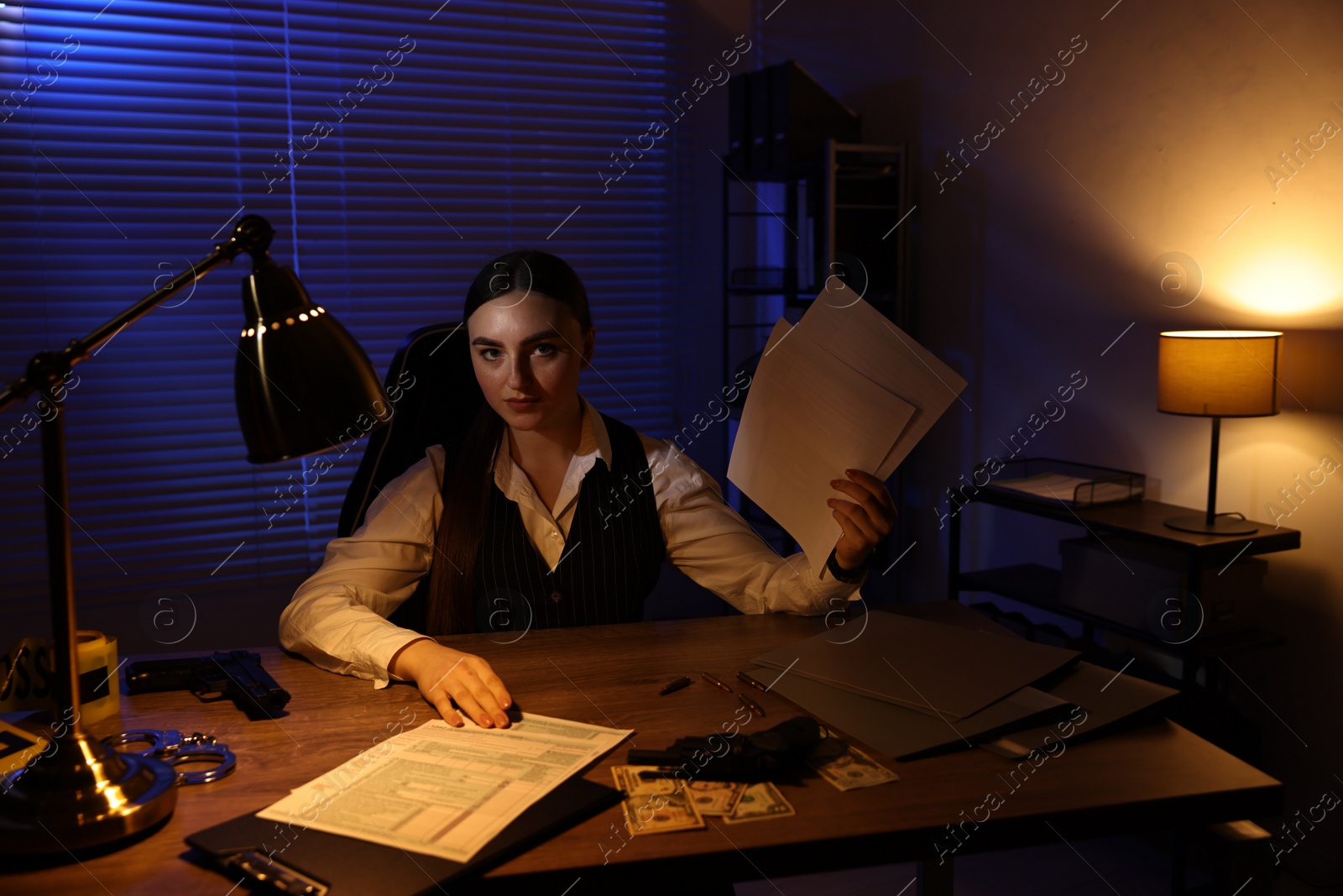 Photo of Professional detective working with documents in office at night