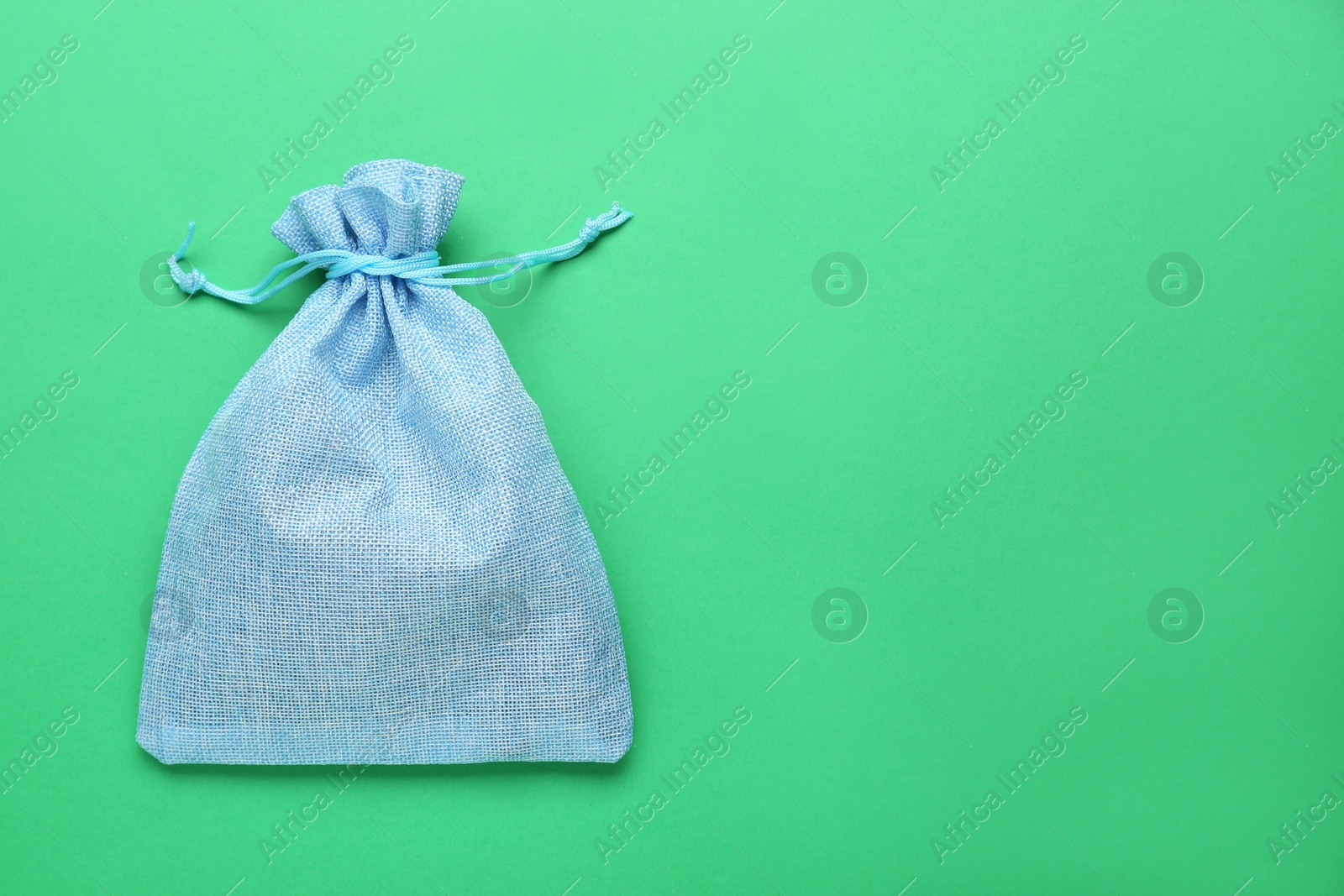 Photo of Light blue burlap bag on green background, top view. Space for text