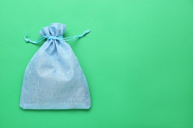 Photo of Light blue burlap bag on green background, top view. Space for text