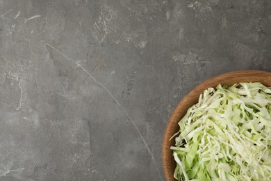 Photo of Chopped cabbage in bowl on grey table, top view. Space for text