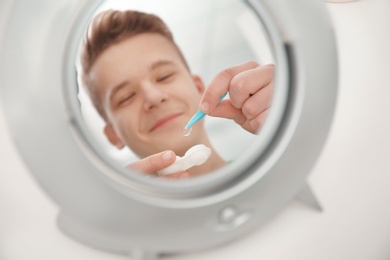 Photo of Mirror reflection of teenage boy taking contact lens from container