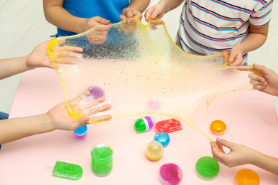 Children playing with slime at table indoors, closeup