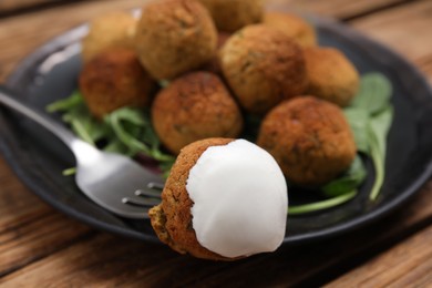 Delicious falafel balls with sauce on table, closeup