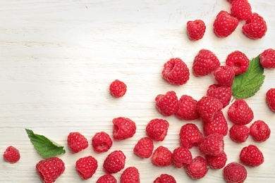 Photo of Ripe aromatic raspberries on wooden table, top view