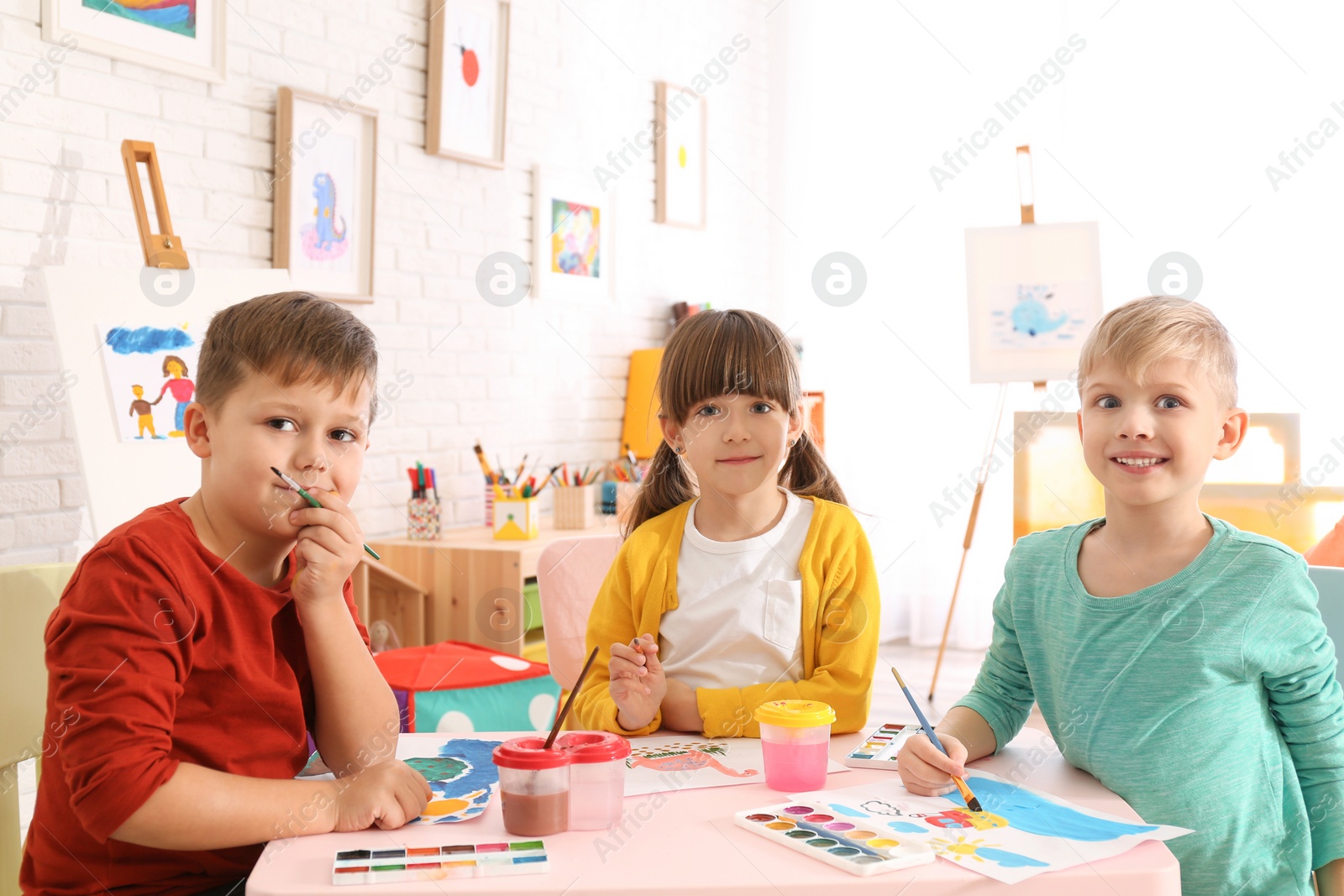 Photo of Cute little children painting at table in room