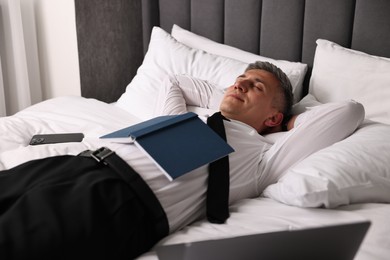 Businessman in office clothes sleeping on bed indoors