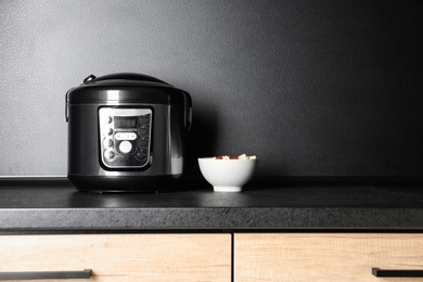 Photo of Modern multi cooker and ingredients on table in kitchen, space for text