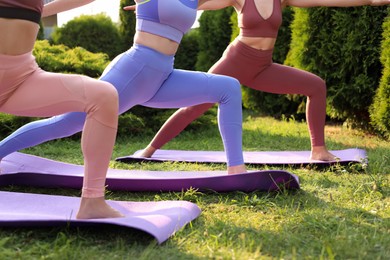 Photo of Women practicing yoga on mats outdoors, closeup