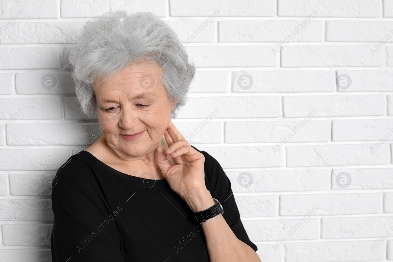 Photo of Portrait of mature woman near brick wall. Space for text