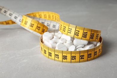 Weight loss pills with measuring tape on table