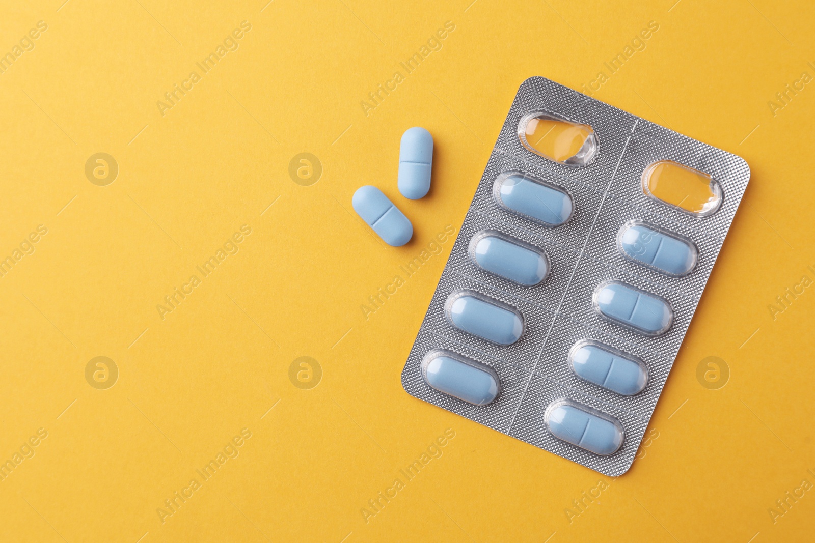 Photo of Pills and space for text on orange background, top view. Potency problem