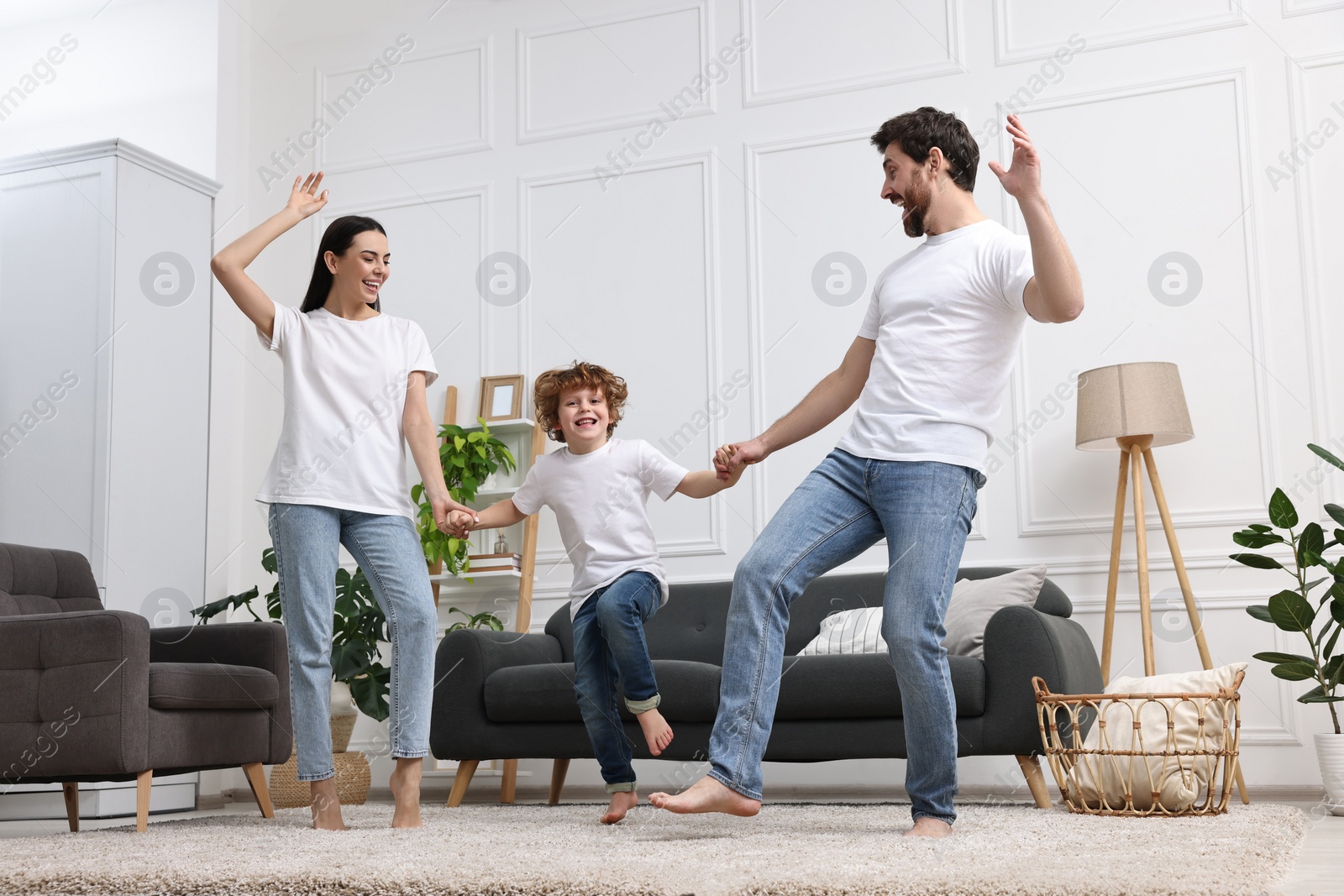 Photo of Happy family dancing in living room, low angle view