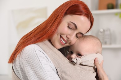 Mother holding her child in sling (baby carrier) indoors