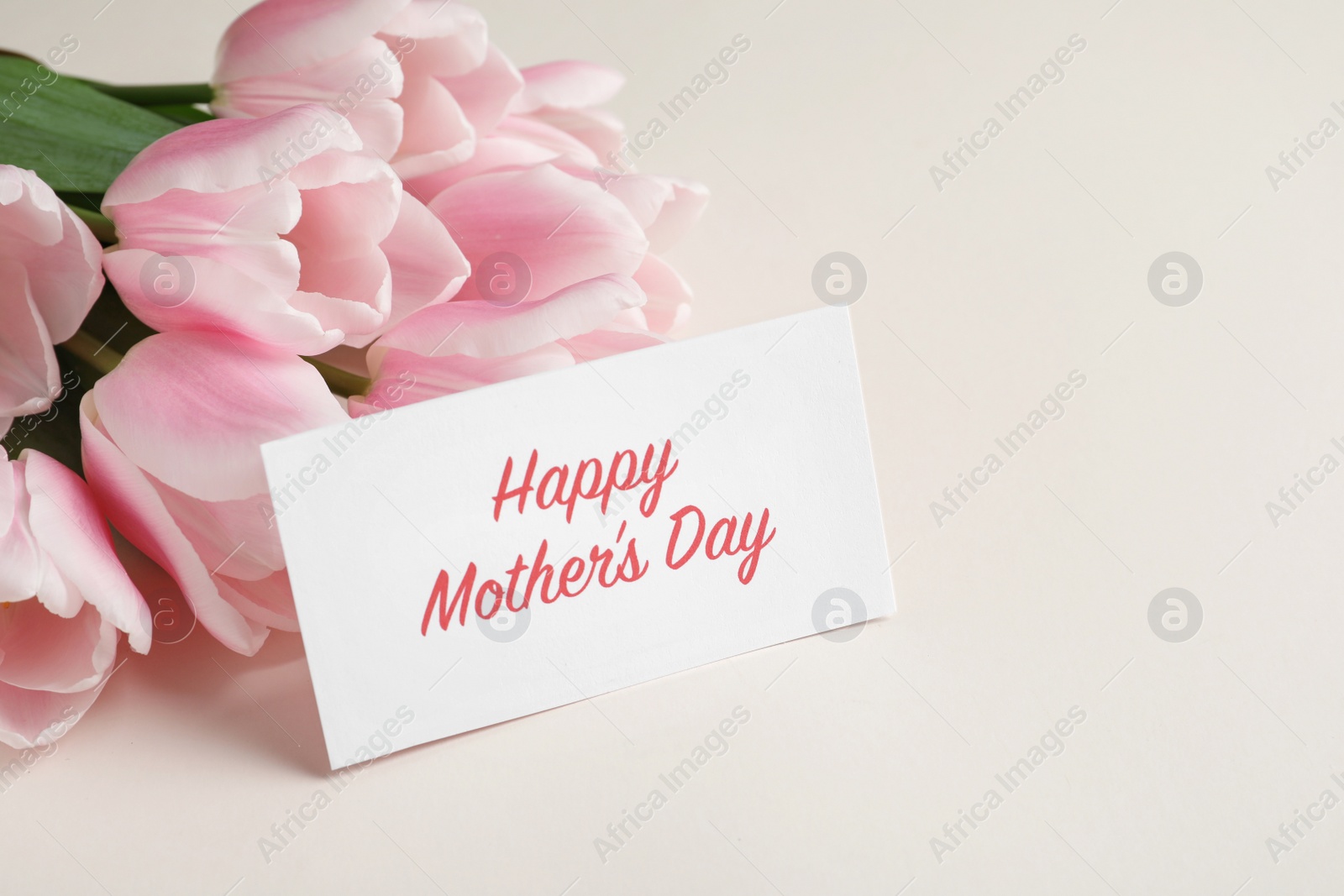 Photo of Beautiful tulips and greeting card with words "Happy Mother's Day" on light background